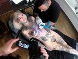 Sascha plays with Amber Luke while she gets tattooed